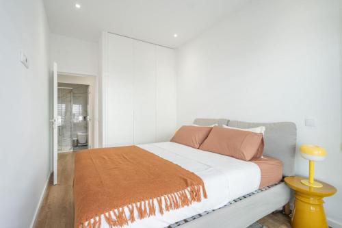 a bedroom with a bed with an orange blanket on it at GO UP - Apartamento no Centro de Guimarães in Guimarães