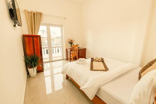 a white room with a bed and a window at Lê Mùi Hotel - Apartment in Da Thien