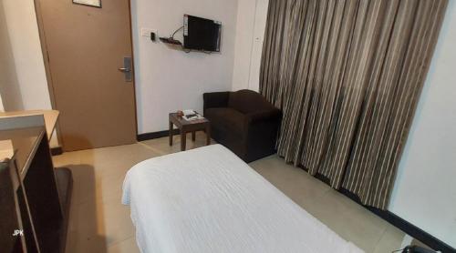 a room with a bed and a chair and a television at Lytton Hotel in Kolkata