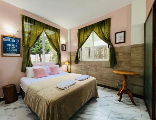 a bedroom with a bed with a table and two windows at Cute Boutique 2 Bedroom 2 Bath in Baños