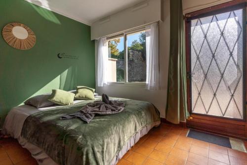 a bedroom with a bed with green walls and a window at Charmant studio avec terrasse, Gare à 200m et parking gratuit in Saint-Cyr-lʼÉcole