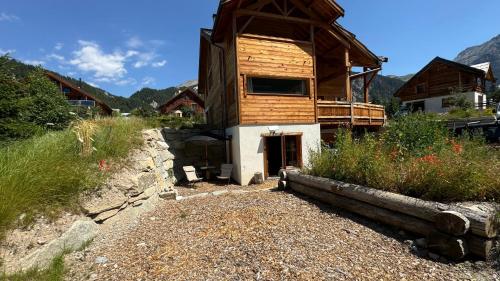 a large wooden cabin with a porch on a mountain at Un Brin Cosy in Névache