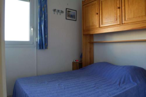 une chambre avec un lit bleu et une fenêtre dans l'établissement Appartement 2 pièces 4 personnes SAINT CYPRIEN PLAGE SC050-156B, à Saint Cyprien Plage