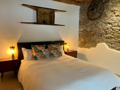 a bedroom with a bed with two lamps and a stone wall at Appartamenti La Rocia in Rocca Pietore