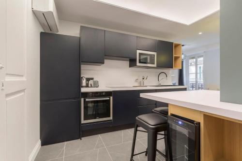 une cuisine avec des armoires noires et un comptoir blanc dans l'établissement Superb apartment in the heart of the peninsula - Air-conditioned, à Lyon