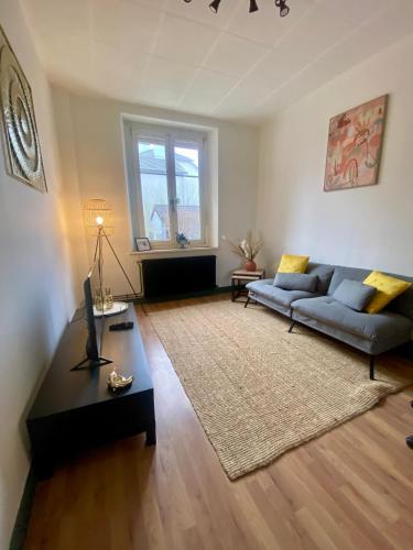 a living room with a couch and a table at Maison paisible, parking privé proche Micropolis in Besançon