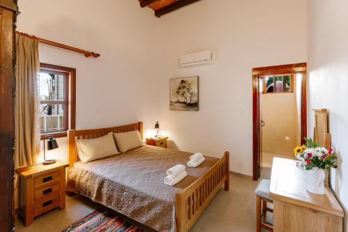 a bedroom with a bed and a table and a window at Iliada's Traditional Stone House in Paphos City