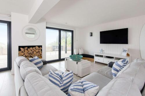 a living room with a couch and a tv at Luxury Seafront Family Home - Indoor Pool in Earnley
