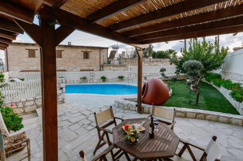 a patio with a table and chairs and a pool at Iliada's Traditional Stone House in Paphos City