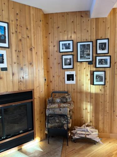 a living room with a fireplace and pictures on the wall at Auberge du Jardin in Petit-Saguenay