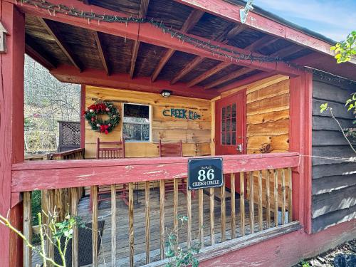 a front porch of a log cabin with a sign at Bearly Behaving Creekside in Maggie Valley