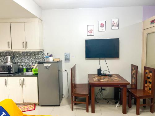 a kitchen with a table and a refrigerator and a television at Sea Residences Sailor in Manila
