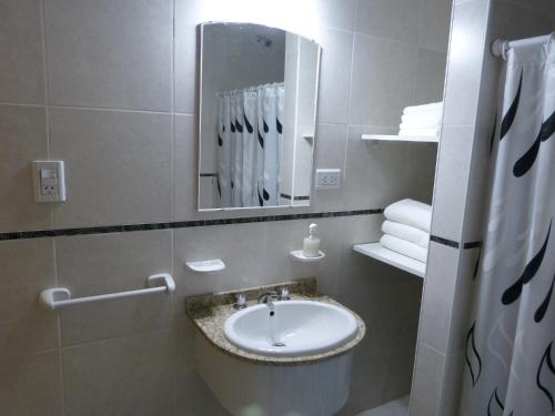 Un baño con lavabo, espejo y toallas. en Santa Isabel Departamentos, en Valle María
