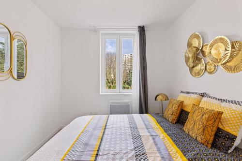 a bedroom with a bed with yellow pillows and a window at T2 cosy - stationnement gratuit in Bourg-en-Bresse