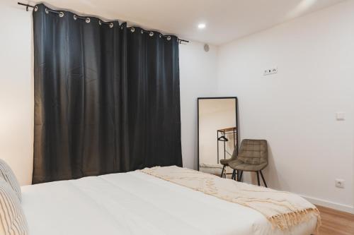 a bedroom with a bed and a black curtain at Santana's Flat in Ribeira Grande