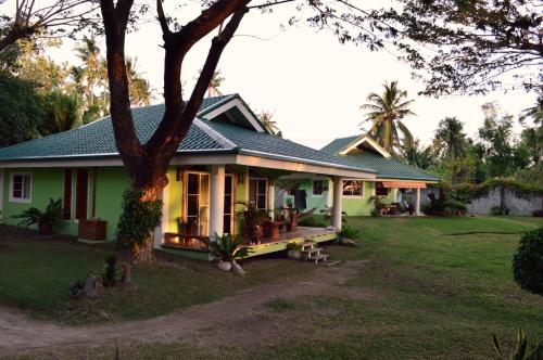 a green house with a tree in front of it at Greenland Residence House in Zamboanguita