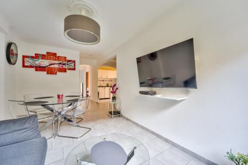 un salon avec une table et une télévision au mur dans l'établissement Modern 2BR Flat - Haut de Nice, à Nice