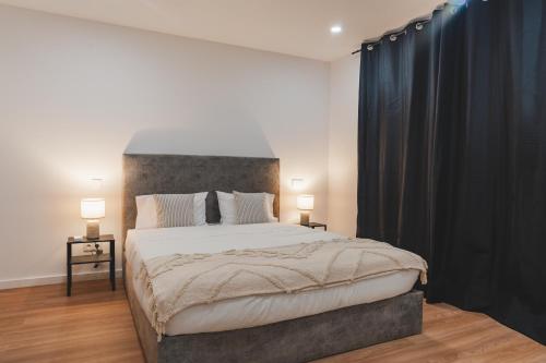 a bedroom with a large bed with black curtains at Santana's Flat in Ribeira Grande