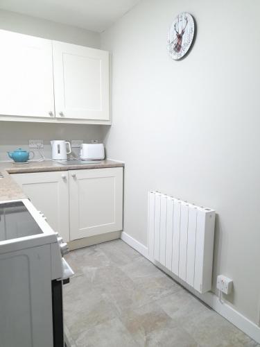a kitchen with white cabinets and a white radiator at 3 St Gilbert Street in Dornoch