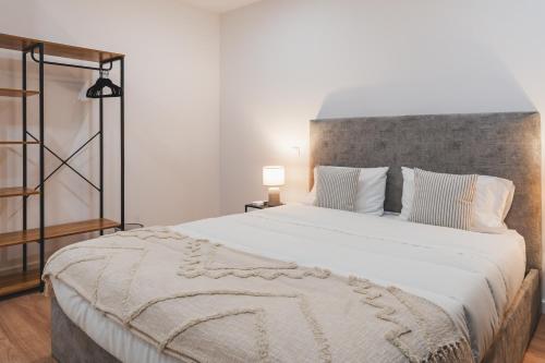 a bedroom with a large bed with white sheets and pillows at Santana's Flat in Ribeira Grande