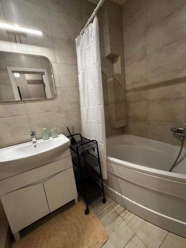 ein Badezimmer mit einer weißen Badewanne und einem Waschbecken und einer Badewanne Tubermott in der Unterkunft Квартира в центральній частині Луцька in Luzk