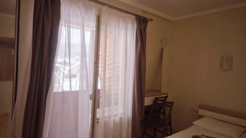 a bedroom with a window with a white curtain at Садиба Святослав in Skhidnitsa