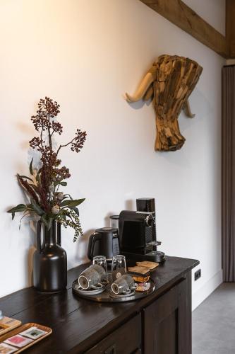 a table with a coffee maker and a vase with flowers at Hoeve BuytenHout in Delft