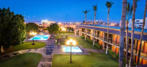 a building with two swimming pools and palm trees at night at Hotel Colonial Mexicali in Mexicali