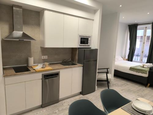 a kitchen with white cabinets and a room with a bed at INSIDEHOME Ciudad del Cine a 3 minutos de la Plaza Mayor in Valladolid