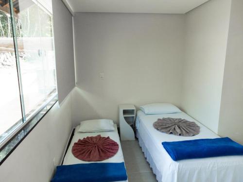 two beds in a small room with a window at Chalé Ribeirão do Meio in Lençóis