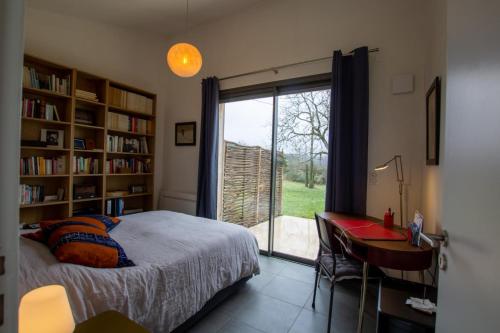une chambre avec un lit, un bureau et une fenêtre dans l'établissement Maison bioclimatique, à Meyrals