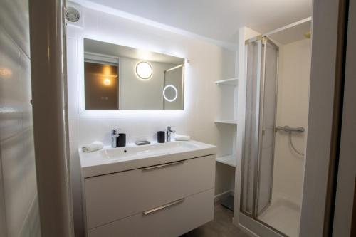 ein weißes Badezimmer mit Waschbecken und Spiegel in der Unterkunft La colombelle in Carsac-Aillac