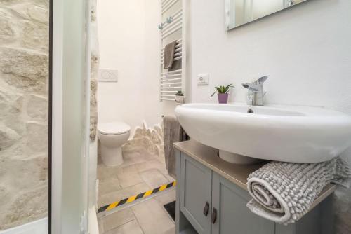 a bathroom with a white sink and a toilet at RivieraRent Dadda House in Orco Feglino