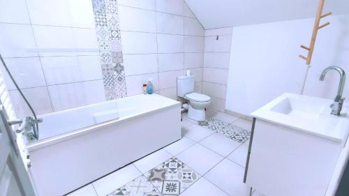a bathroom with a tub and a toilet and a sink at Les rosieres 2 in Dom-le-Mesnil