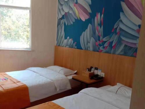 a bedroom with two beds and a painting on the wall at PAI Hotels Shijiazhuang Railway Station West Square in Shijiazhuang