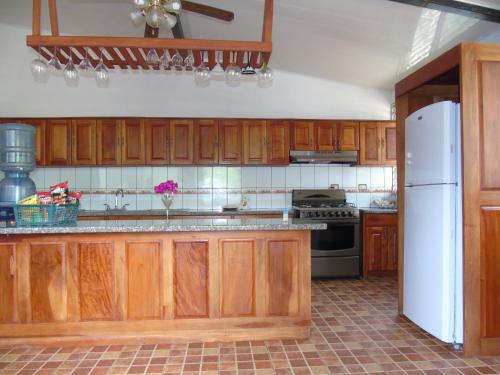 a kitchen with wooden cabinets and a white refrigerator at Hostal Villas Mexico in San Juan del Sur