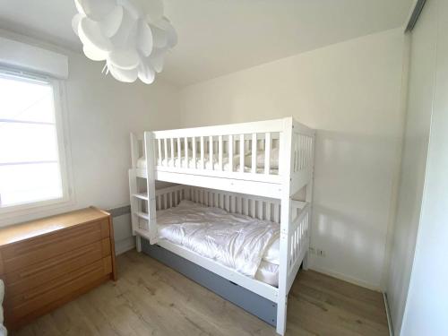 Ce lit superposé blanc se trouve dans un dortoir doté d'un lustre. dans l'établissement Appartement avec WIFI, balcon au centre de PERROS-GUIREC - Réf 959, à Perros-Guirec