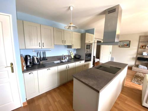 une cuisine avec des armoires blanches et un comptoir noir dans l'établissement Appartement avec WIFI, balcon au centre de PERROS-GUIREC - Réf 959, à Perros-Guirec