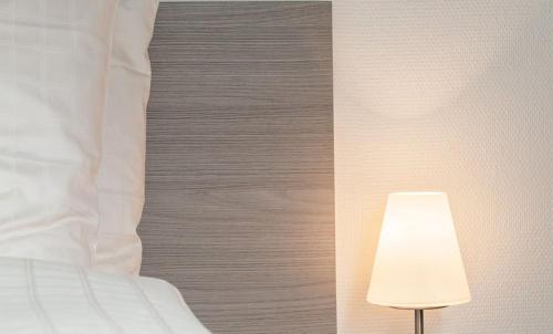 a bedroom with a white bed and a lamp at EMA House Serviced Apartments Aussersihl in Zürich