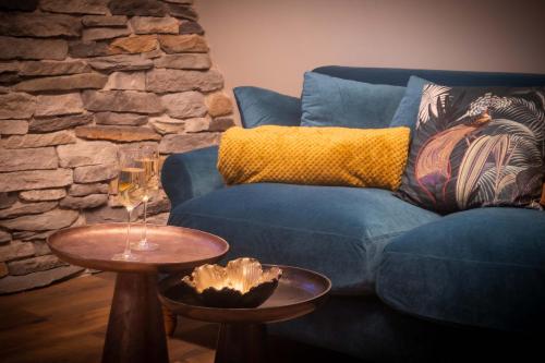 a living room with a blue couch and two tables at Suite & SPA 1566 Benfeld in Benfeld