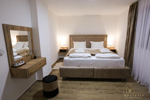 a bedroom with a large bed and a mirror at Helvetia Apartments in Jajce
