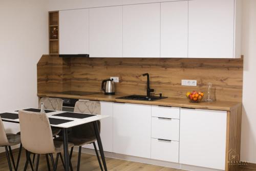 a kitchen with white cabinets and a table at Helvetia Apartments in Jajce