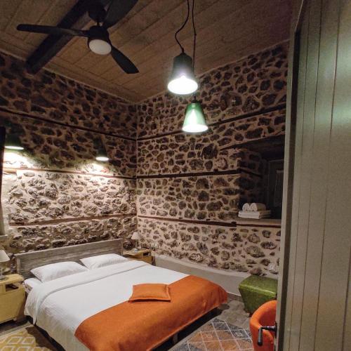 a bedroom with a bed in a room with stone walls at Bayiri Petit Pension in Litochoro