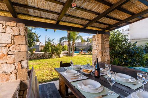 a wooden table with plates and wine glasses on it at Villa Alida by Vivimy in Andrano