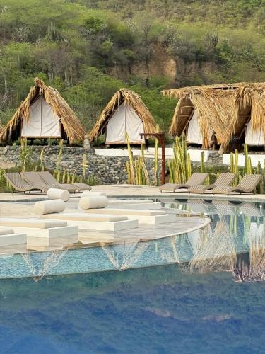 a resort pool with chairs and tents in the background at Izotal Bioluxury Hotel in Taminango