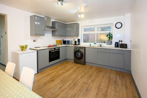 a kitchen with white cabinets and a washer and dryer at LITTLE COTO Fully Equipped South West Home By STAE-Homes in Bristol