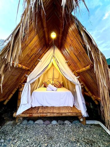 a bed in a thatch roofed tent at Izotal Bioluxury Hotel in Taminango