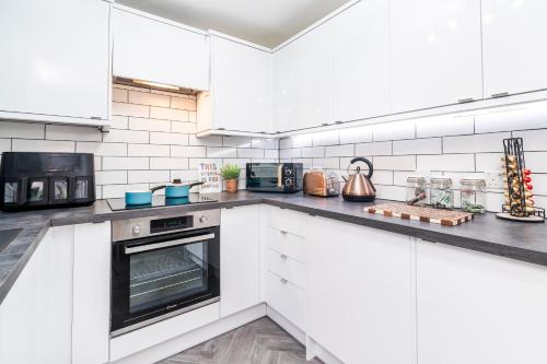 a kitchen with white cabinets and an oven at 2-Bed House with Garden & Free Parking, Quiet Location, Cwmbran in Cwm-brân