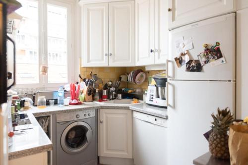 La cuisine est équipée d'un réfrigérateur blanc et d'un lave-vaisselle. dans l'établissement Bright Haussmann apartment near Nation, à Paris