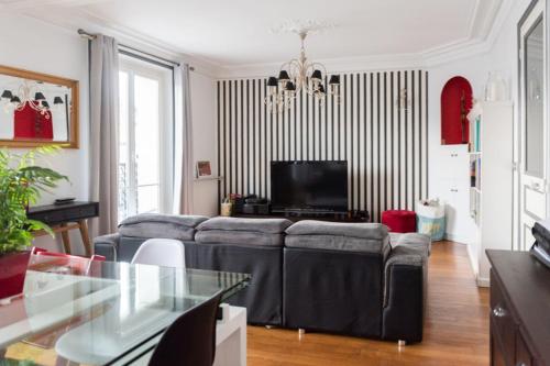 un salon avec un canapé et une télévision dans l'établissement Bright Haussmann apartment near Nation, à Paris